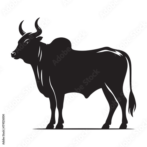 Silhouette of a majestic bull with prominent horns standing on a grassy field