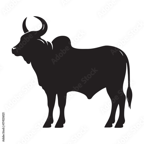 Silhouette of a majestic bull with prominent horns standing on a grassy field