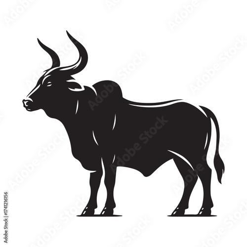Silhouette of a majestic bull with prominent horns standing on a grassy field