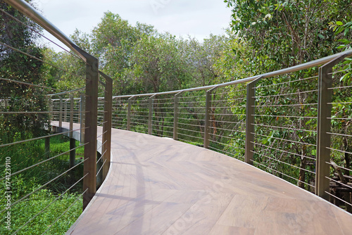 Curving wooden boardwalk amongst the park in sunlight