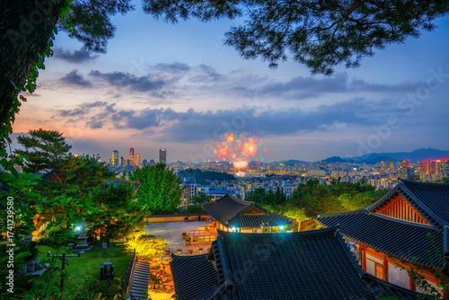 Seoul skyline with fireworks seen from a Korean Hanok Village at dusk.