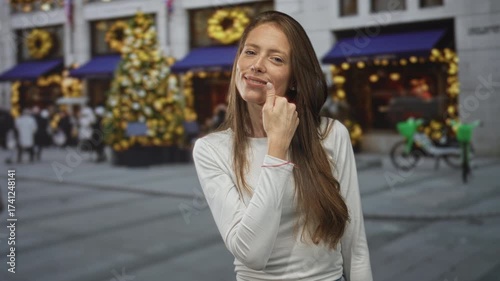 Wallpaper Mural Woman touching chin on city street near decorated shop windows and christmas tree; thoughtful contemplation. Torontodigital.ca