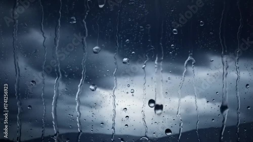 Rain droplets on a window pane with dark stormy clouds outside  