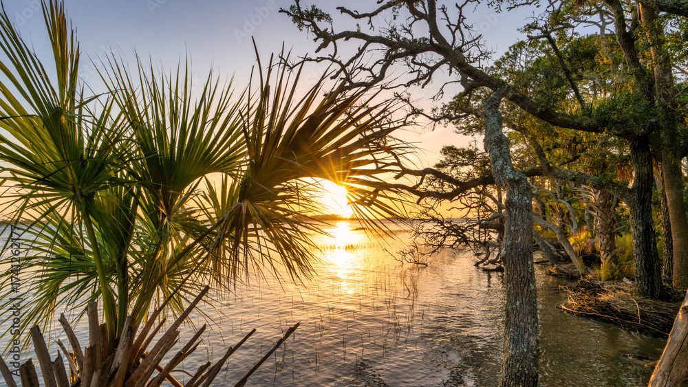Fototapeta premium Sunset over Beaufort, South Carolina, showcasing coastal landscapes and palm trees along the water's edge