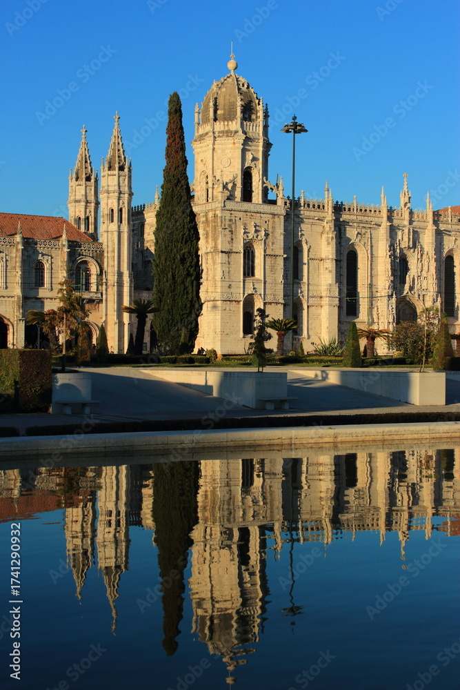 Obraz premium Portugal, Lisbon, Belem. Hieronymites Monastery - Mosteiro dos Jeronimos. Built in Gothic-Manueline style. Reflected on fountain water. One of Lisbon's most visited monuments. Late afternoon sunshine.