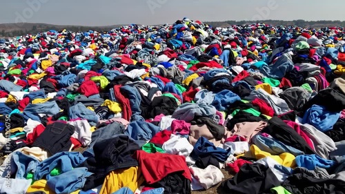 Massive landfill filled with colorful piles of discarded clothes from fast fashion waste industry