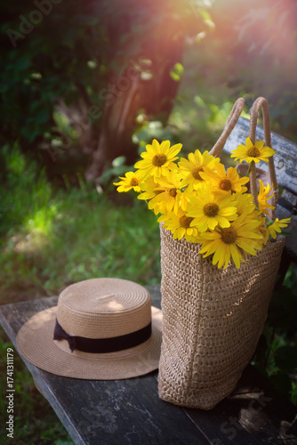 Wild flowers in a beautiful straw bag and a straw hat.