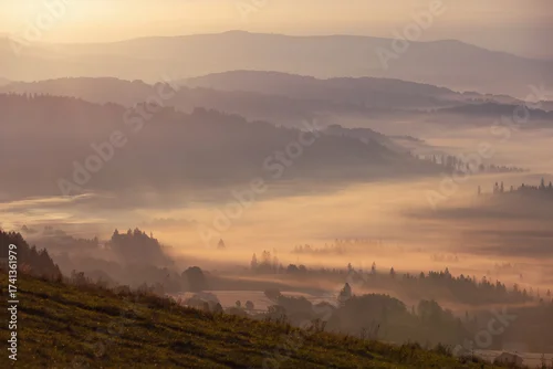 Fototapeta samoprzylepna Jesienny widok na góry i spokojny krajobraz z mgłą i słońcem o świcie, Beskidy, Polska, tło lub fototapeta
