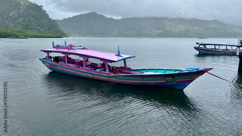 Colorful boat floats peacefully on calm water near mountains.