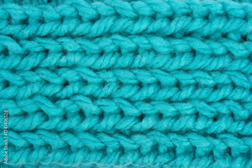 A detailed macro shot captures the dense texture of chunky knit fabric with prominent horizontal rows in a rich teal-blue color