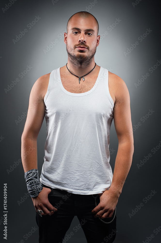 Fototapeta premium Confident Bald Man Posing in White Tank Top with Dramatic Lighting