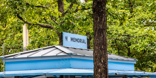 Φωτογραφία Blue 9/11 Memorial sign atop kiosk surrounded by green trees in New York City