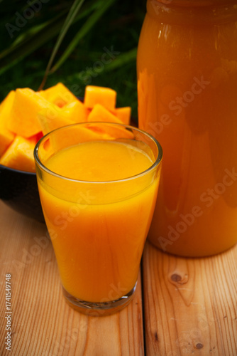 Harvesting fresh pumpkin juice displayed in a glass and pitcher on a wooden board close-up