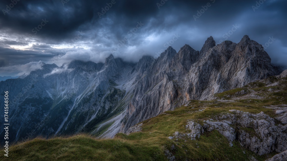 Fototapeta premium The sky is dark and cloudy, and the mountains are covered in snow. The scene is serene and peaceful, with the mountains towering over the landscape