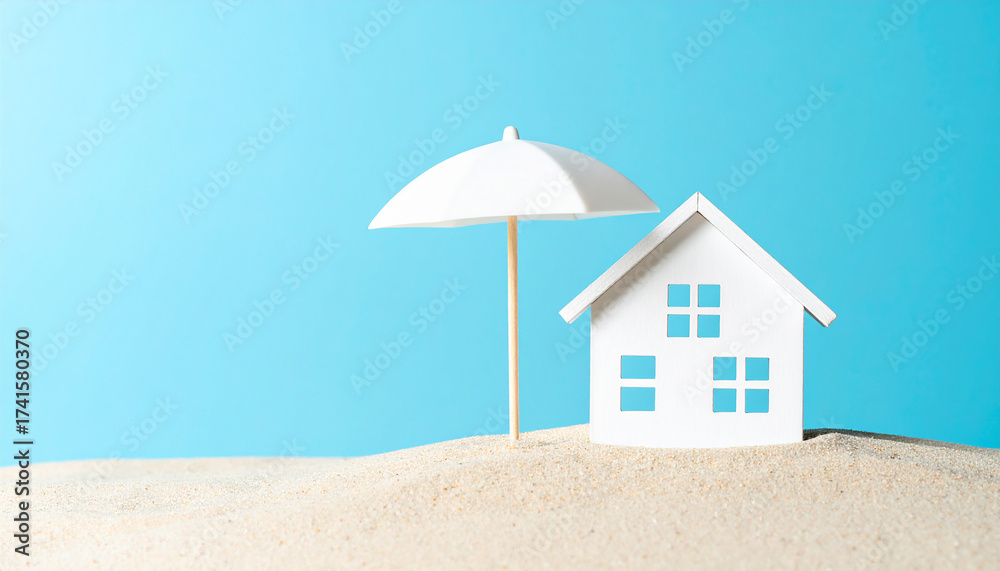 Obraz premium Minimalist white house model with beach umbrella on sandy surface. Summer home insurance.