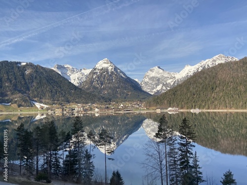 Reflection of the only slightly snow-covered Alps in Lake Achensee with a view of Maurach, Austria, Europe, April 12, 2022