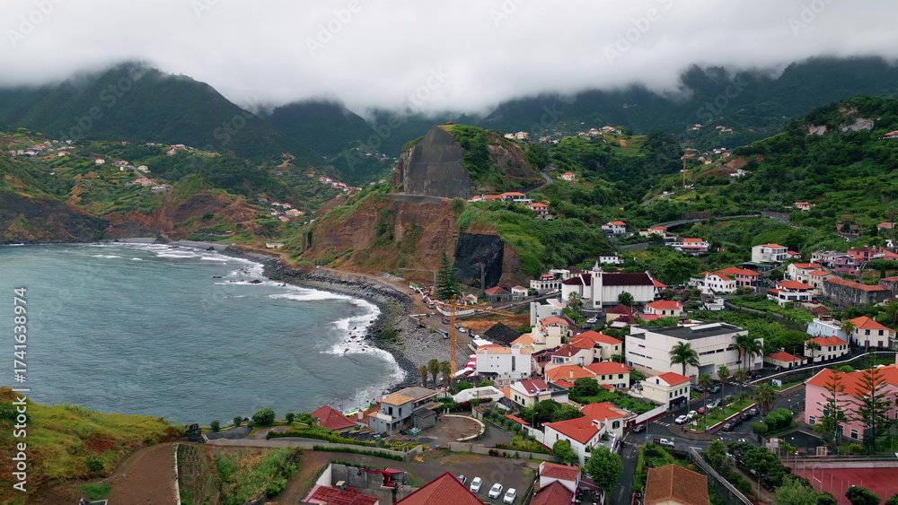 Obraz premium Cozy Mediterranean village stretching on green slopes washed ocean aerial view.