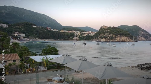 Real-time video of calm Ionian Sea in Parga Greece. Boats floating near the coast, Venetian castle and clear blue water in daylight create peaceful Mediterranean travel scenery.