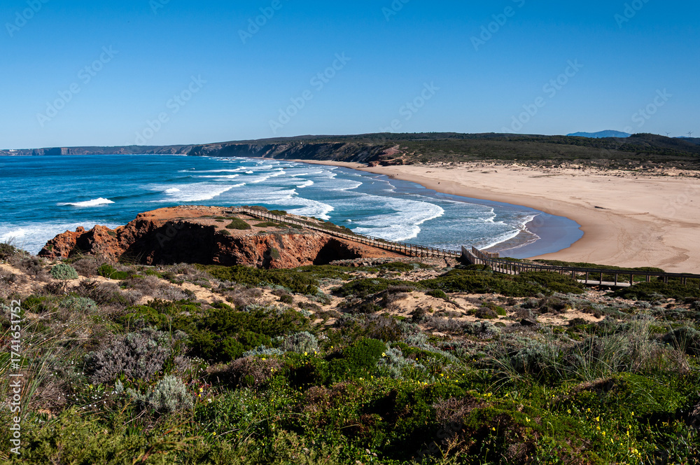 Obraz premium Praia da Bordeira, Algarve, Portugal. The blue sky and calm water disguise the often wild and windswept Atlantic west coast of Portugal. 