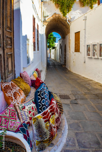 Colorful decorative pillows in the narrow alley with whitewashed walls, Lindos, Rhodes, Greece