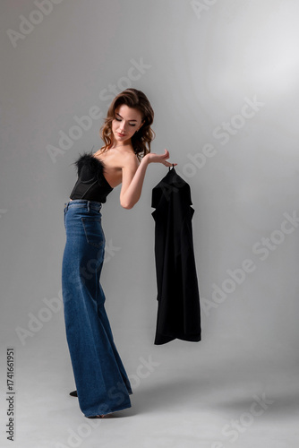 Model showcases stylish black outfit against neutral backdrop during fashion photoshoot