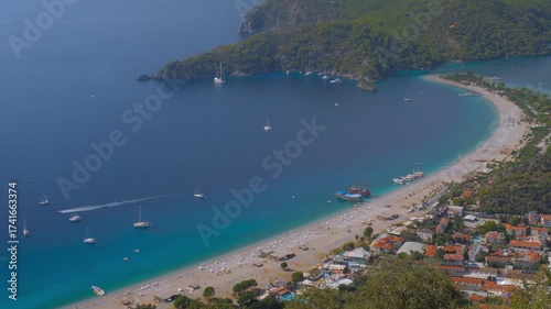 Time lapse: high angle view from the Lycian Way above the Blue Lagoon in Oludeniz, with paragliders gliding and boats sailing through the bay's turquoise waters - dynamic timelapse scene