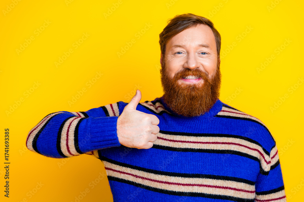Fototapeta premium Cheerful bearded man giving a thumbs-up in colorful sweater against vibrant yellow background
