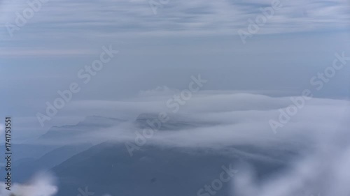 Mountain Peaks Emerging Through Clouds and Mist in Atmospheric Blue Landscape