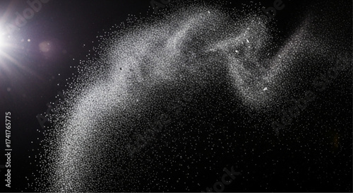 An ethereal explosion of radiant light and fine particles gracefully drifts across a dark background. The image captures the dance of matter, a captivating visual symphony.