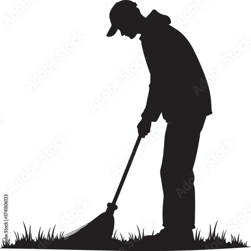 Silhouette of person in baseball cap sweeping grass