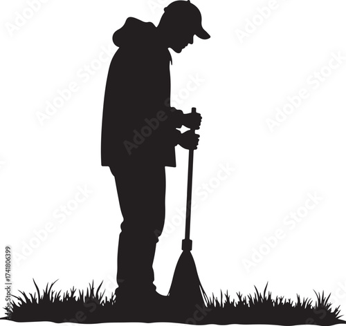 Silhouette of person in cap holding broom in grass