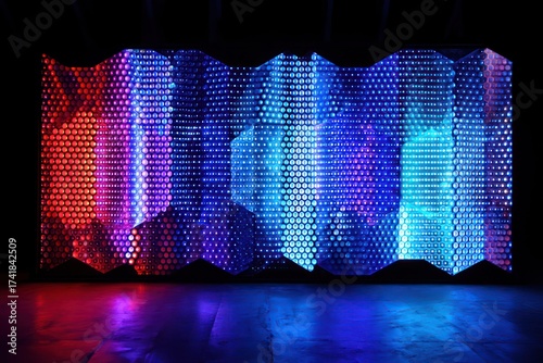 Illuminated perforated panel with red blue and purple lights on a reflective surface in a dark room