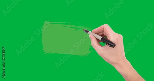 Hand holding a pen writing over green paint stain against copy space on transparent background