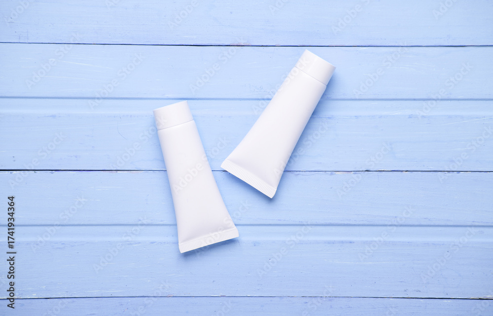 Fototapeta premium White cream tubes on blue wooden background. Template for design. Beauty concept