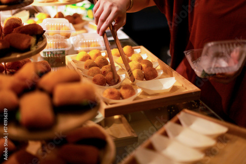 Photography close up of a woman's hands serving bitterballen on a wooden tray