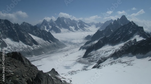 Majestic alpine scenery featuring snowcapped peaks rugged mountainscape over a valley filled with fog aerial perspective panoramic vista winter mood