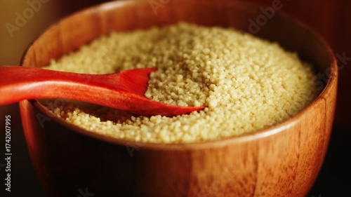 Perfect uncooked couscous preparation in a wooden bowl with a red spoon