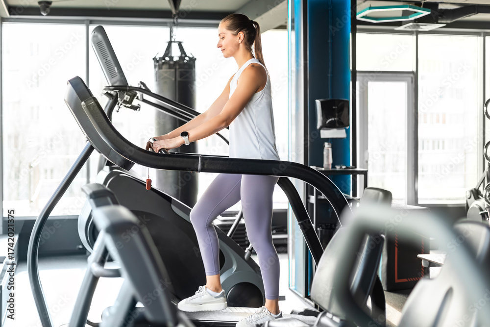 Fototapeta premium Sports woman running on the treadmill in the gym. Cardio training.