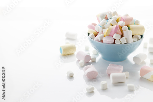 Colorful marshmallows in a bowl on white table background.