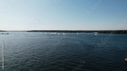 Small sailing yachts and motorboats sail on the lake. Aerial shooting of water recreation