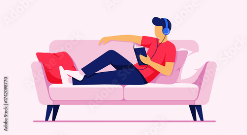 Young man wearing headphones, listening to music or audiobook, and reading book while relaxing on comfortable couch in modern living room, enjoying leisure time