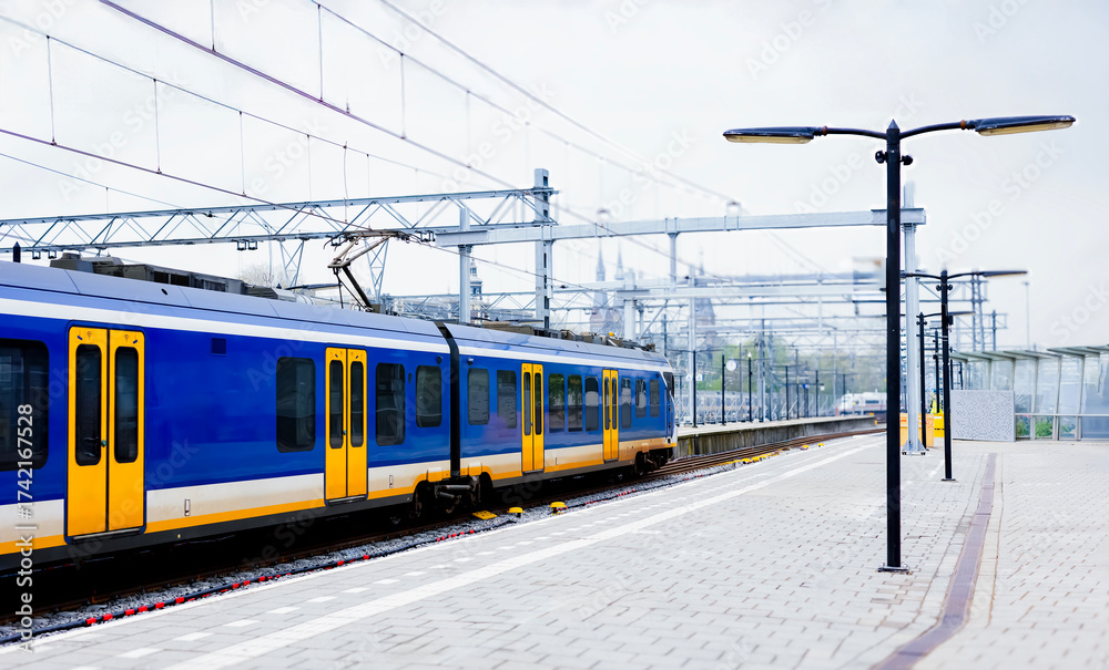 Fototapeta premium A local blue train no logo departs from the station in the Netherlands.