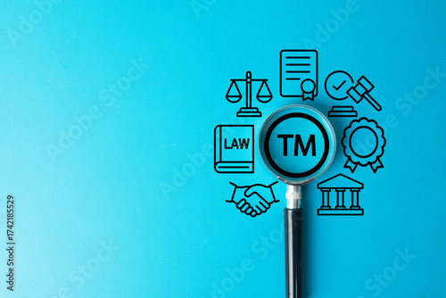 Trademark and intellectual property law concept. A magnifying glass focuses on the TM symbol, surrounded by icons of justice, contracts, and regulations for brand name and logo protection.