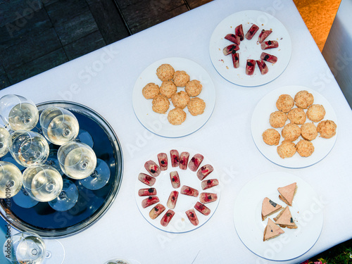 Buffet gastronomique lors d’une soirée d’entreprise sur un rooftop à Paris, avec verres de vin blanc pétillant, mignardises et toasts au foie gras sur nappe blanche.