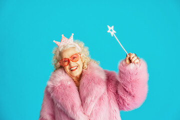 Beautiful senior old woman wearing fancy party clothes acting on a colored background in studio