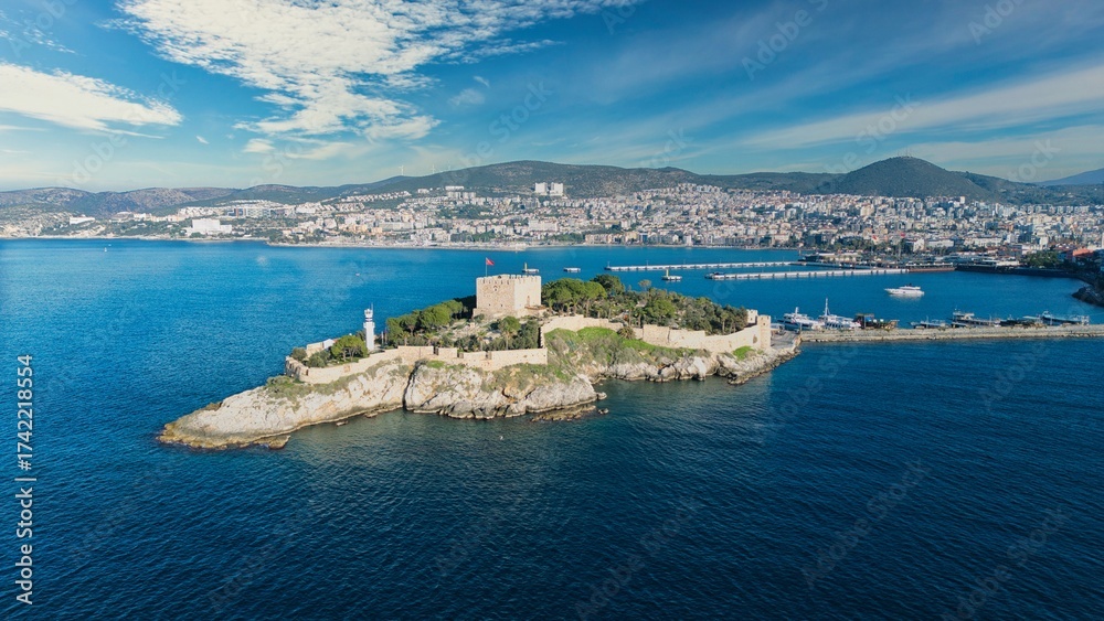Fototapeta premium Aerial View of Pigeon Island (Güvercinada) in Kusadasi, Turkey – Historic Fortress Surrounded by the Aegean Sea under Light Clouds