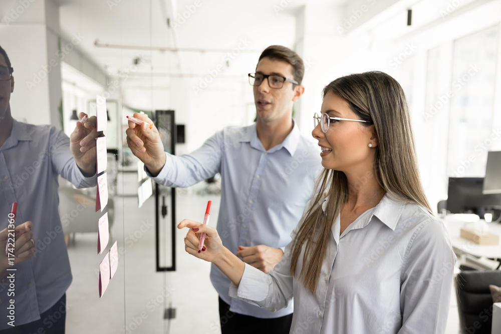 Fototapeta premium Latin couple of businesspeople planning tasks at glass scrum board