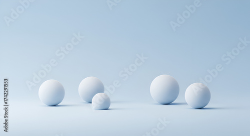 Minimalistic composition of spheres with varying sizes on a light blue background