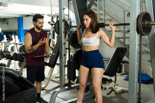 Woman doing squats with personal trainer coaching at gym