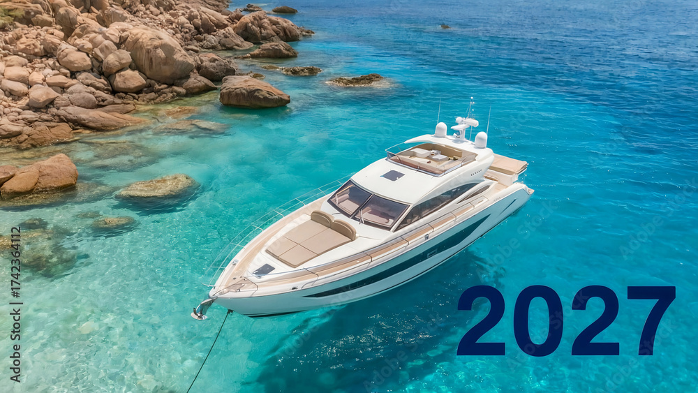 Fototapeta premium Luxury yacht anchored in crystal clear turquoise water with rocky coastline and 2027 text, tropical travel and summer vacation concept symbolizing freedom, adventure, and relaxation at sea